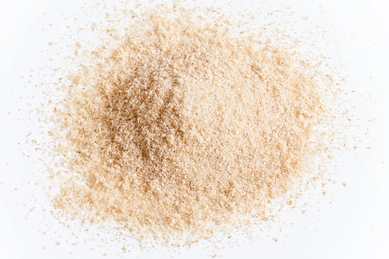 A pile of fine beige spice powder scattered on a white surface
