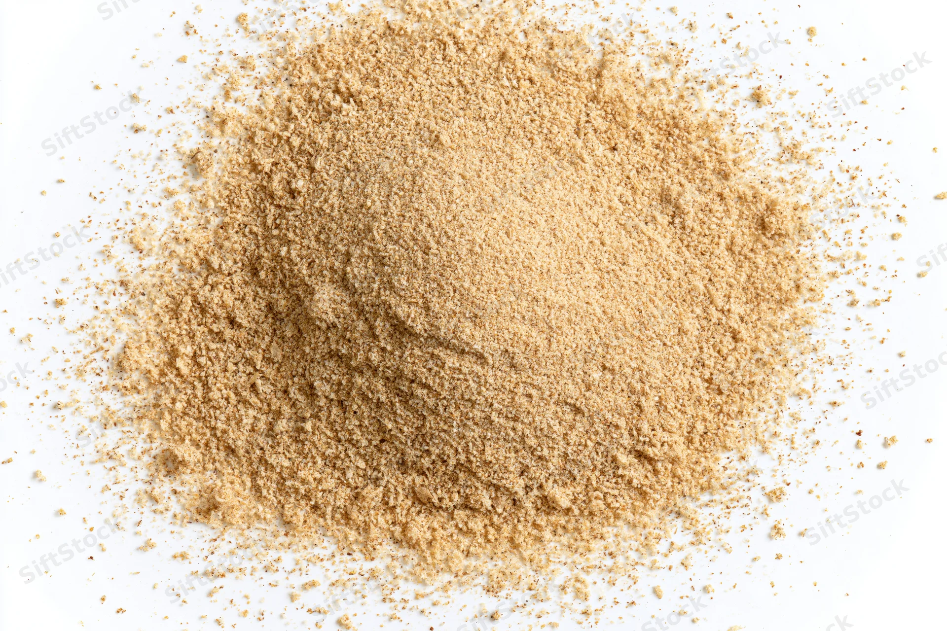 A mound of fine beige spice powder scattered on a white surface