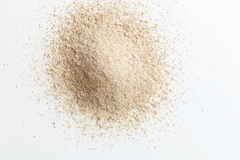 Heap of fine beige spice powder scattered on white surface