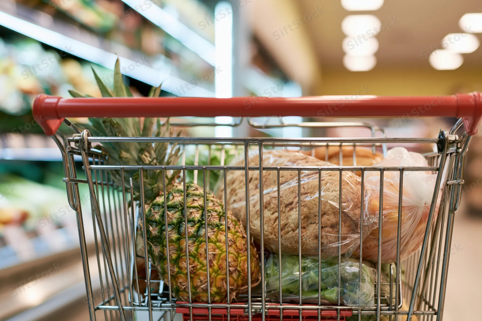 Metal shopping cart filled with groceries in supermarket aisle