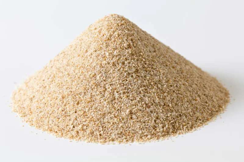 Conical pile of coarse dry sand on white background
