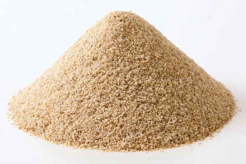 Conical pile of coarse dry sand on white background