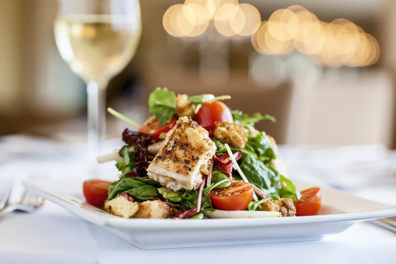 Plated salad with crispy chicken and cherry tomatoes on a restaurant table