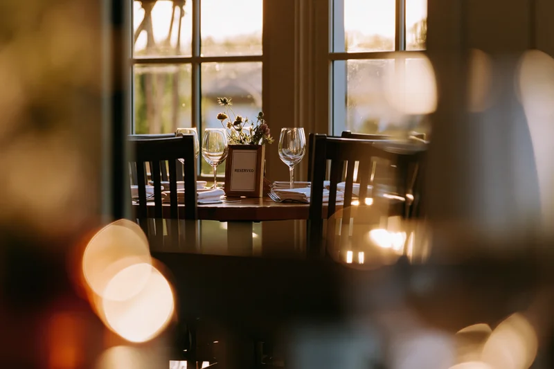 Reserved table set for dinner in a restaurant dining room with warm light through windows