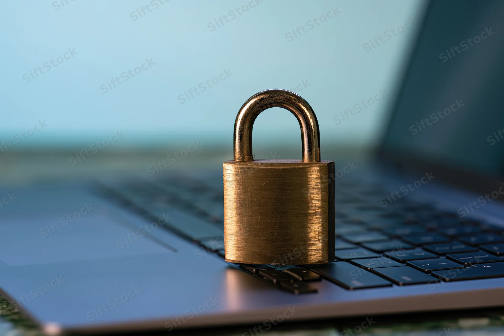 Brass padlock resting on laptop keyboard symbolizing digital security