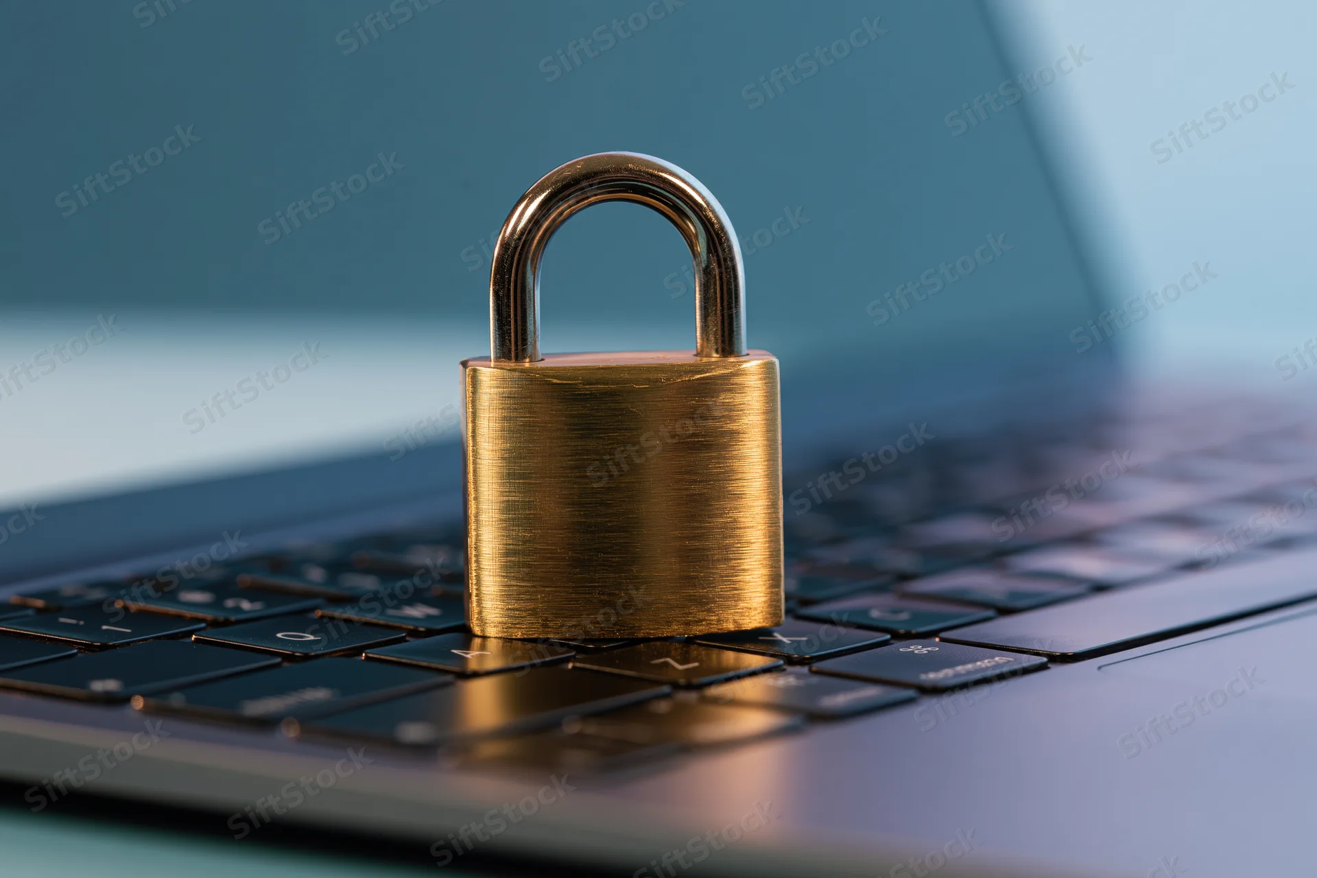 Brass padlock resting on laptop keyboard symbolizing digital security