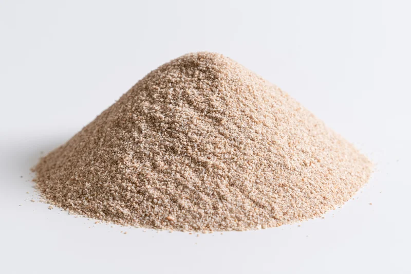 A small pile of fine-grain sand on a white surface