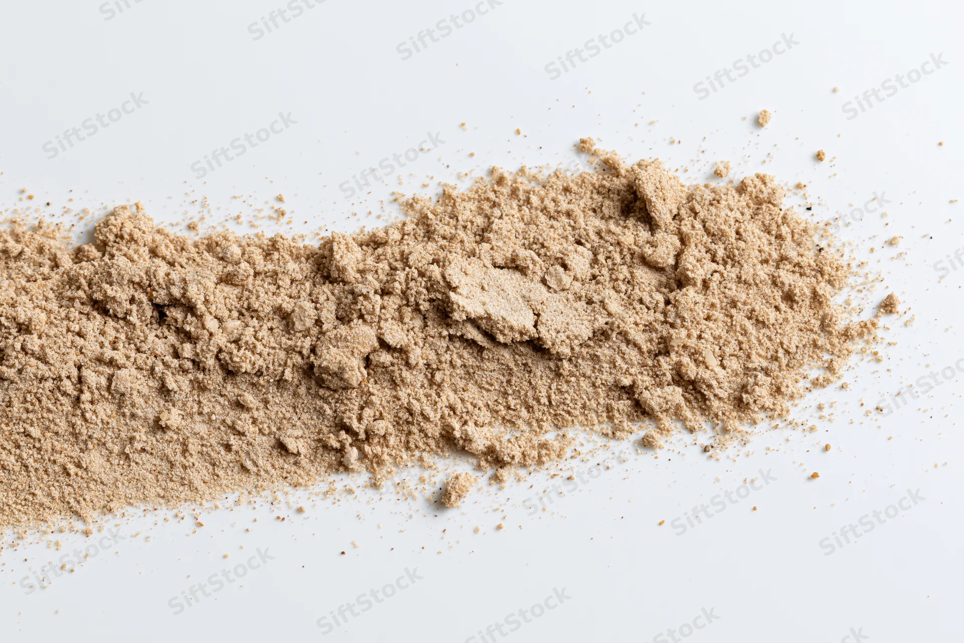 Fine dry sand scattered in a low horizontal pile on white background