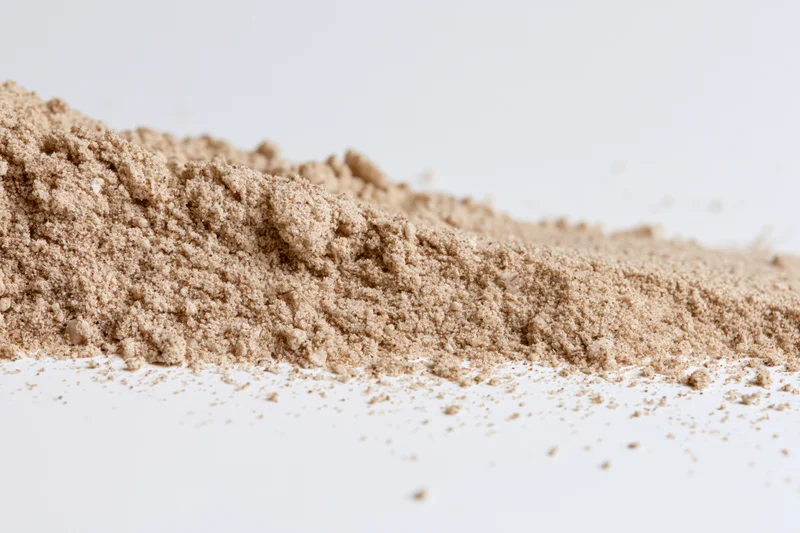 Fine dry sand piled and scattered on a white surface