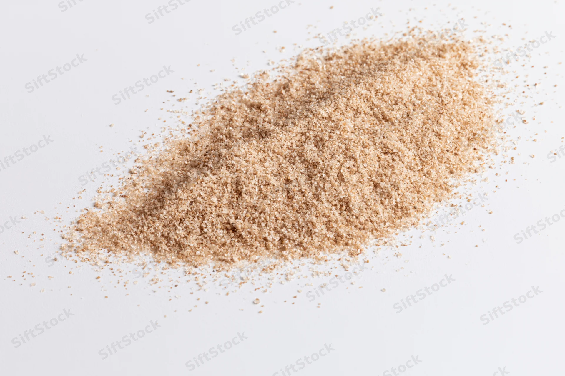 A small scattered pile of fine dry sand on a white surface