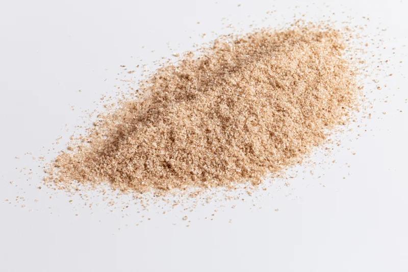 A small scattered pile of fine dry sand on a white surface