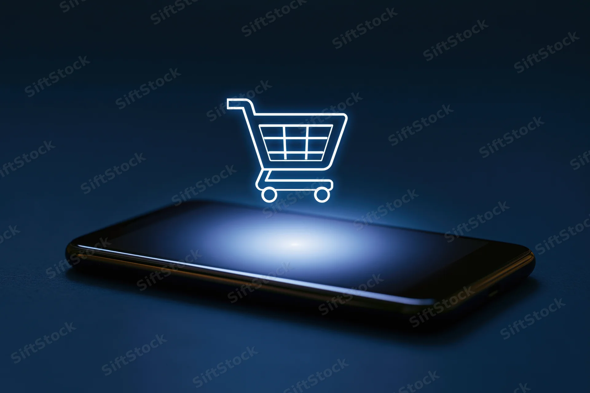 Smartphone with glowing shopping cart icon hovering above its screen on dark surface