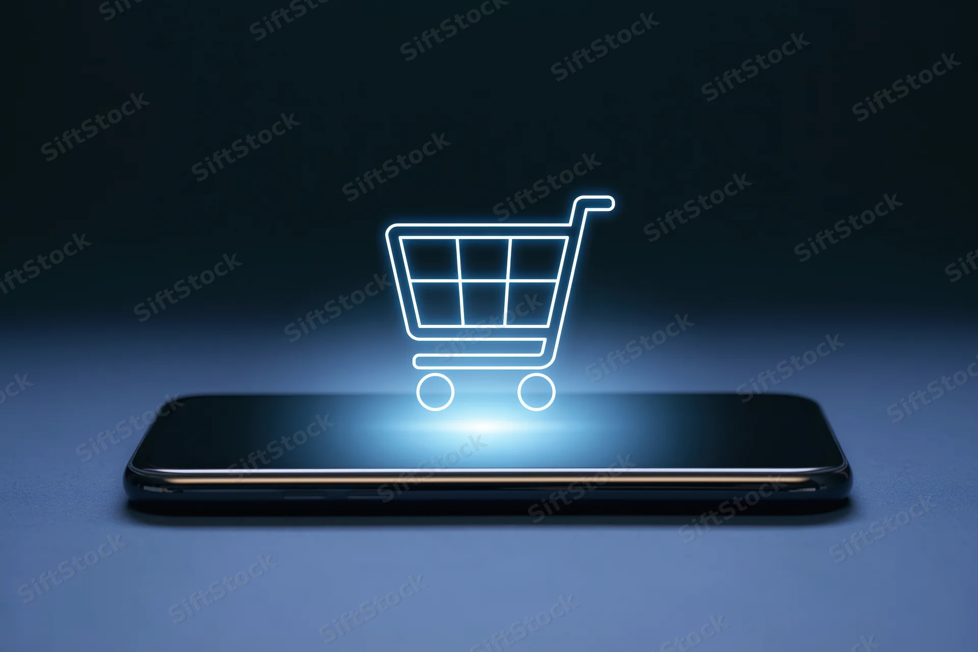 Smartphone lying flat with glowing shopping cart hovering above its screen on dark surface
