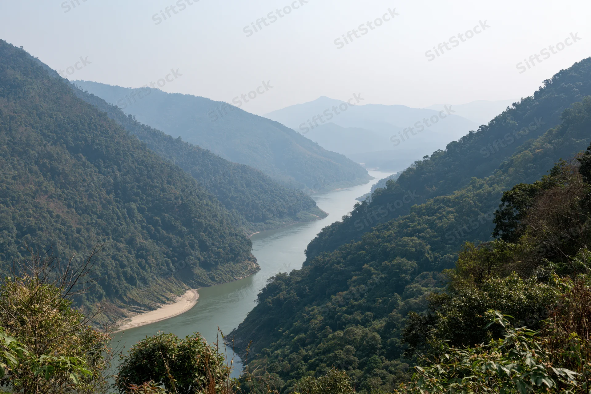 Wide river winding through deep forested mountain valley