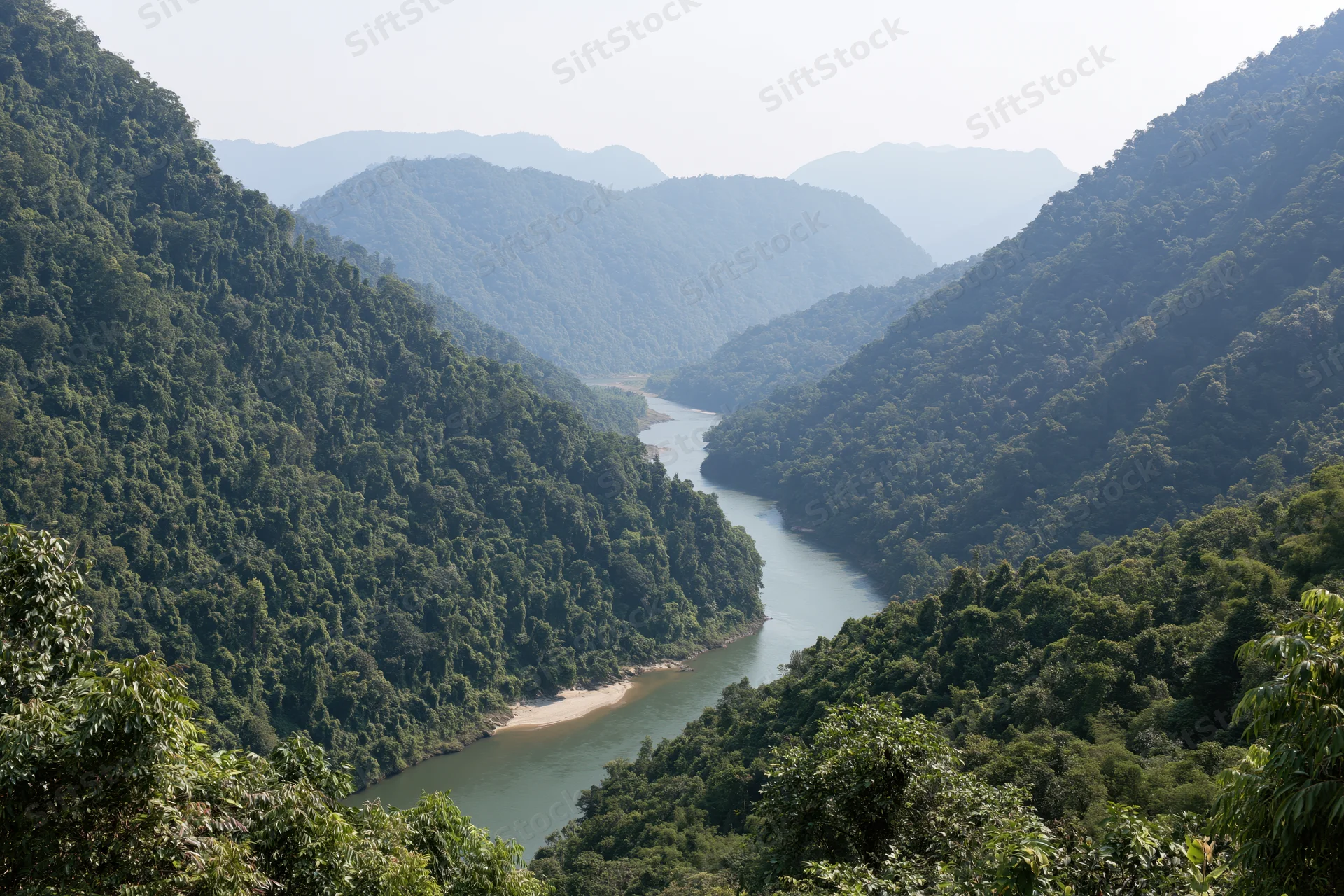 Wide river winding through deep forested mountain valley
