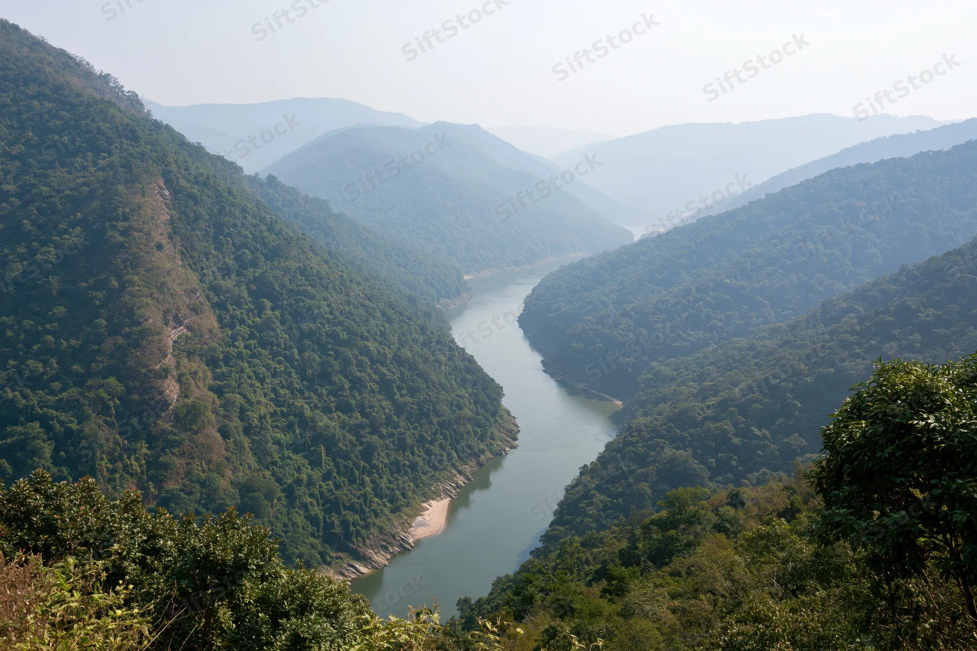 Wide river winding through deep forested mountain valley