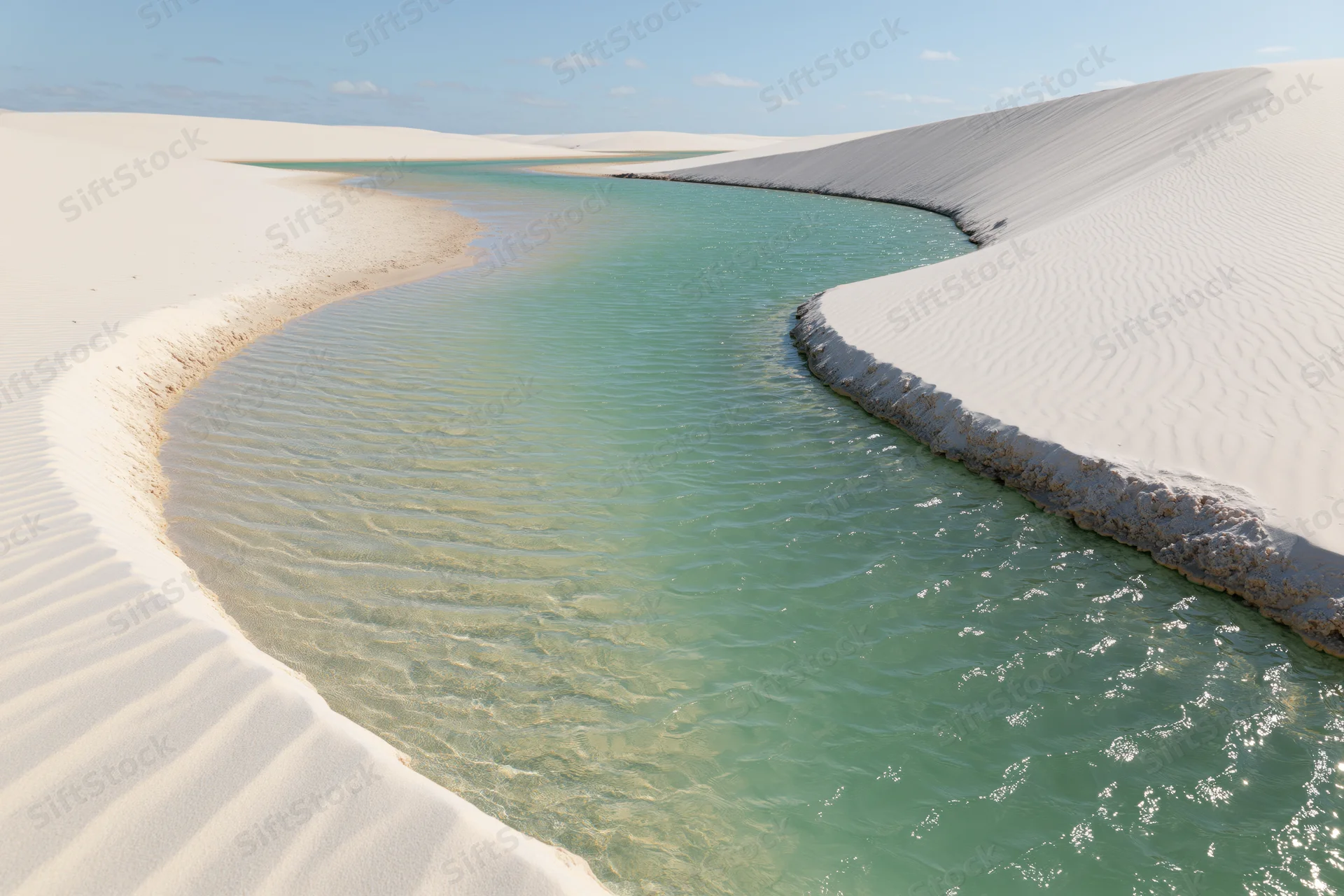 Turquoise lagoon winding between white sand dunes in a desert landscape