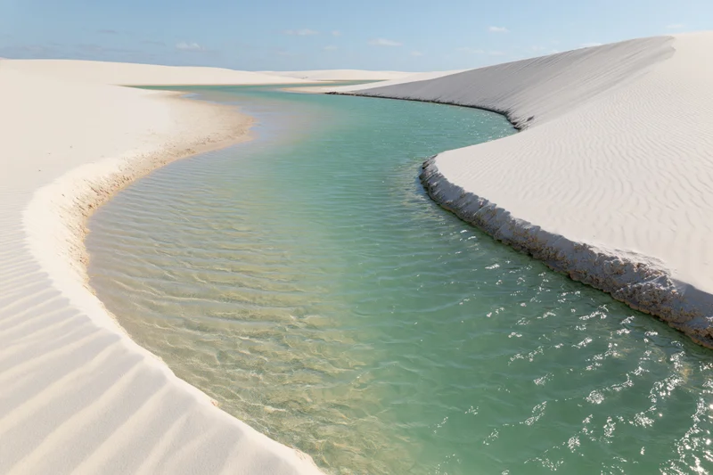 Turquoise lagoon winding between white sand dunes in a desert landscape