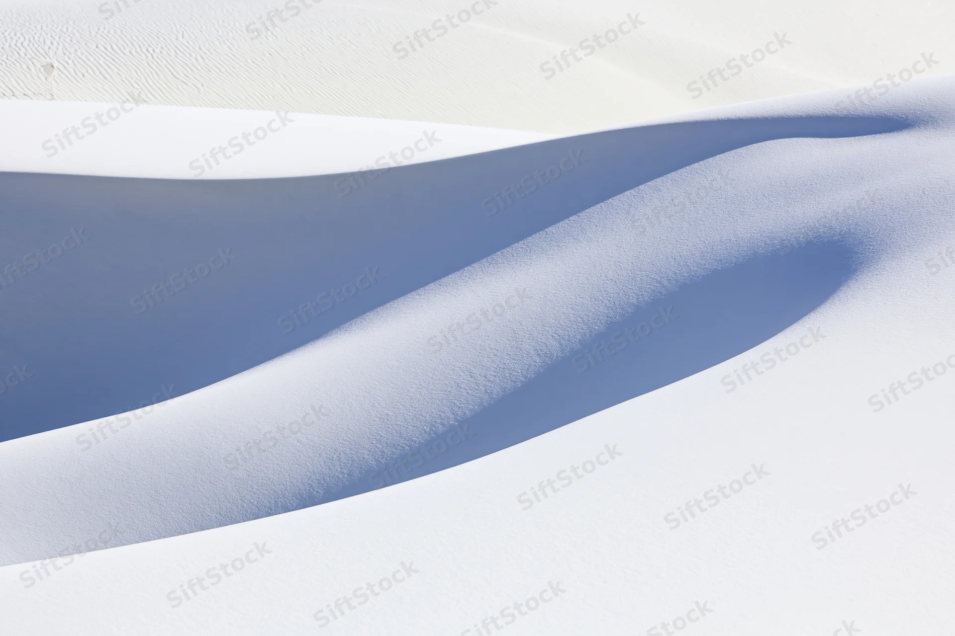 Smooth white gypsum sand dunes forming flowing curves under bright light in a desert landscape