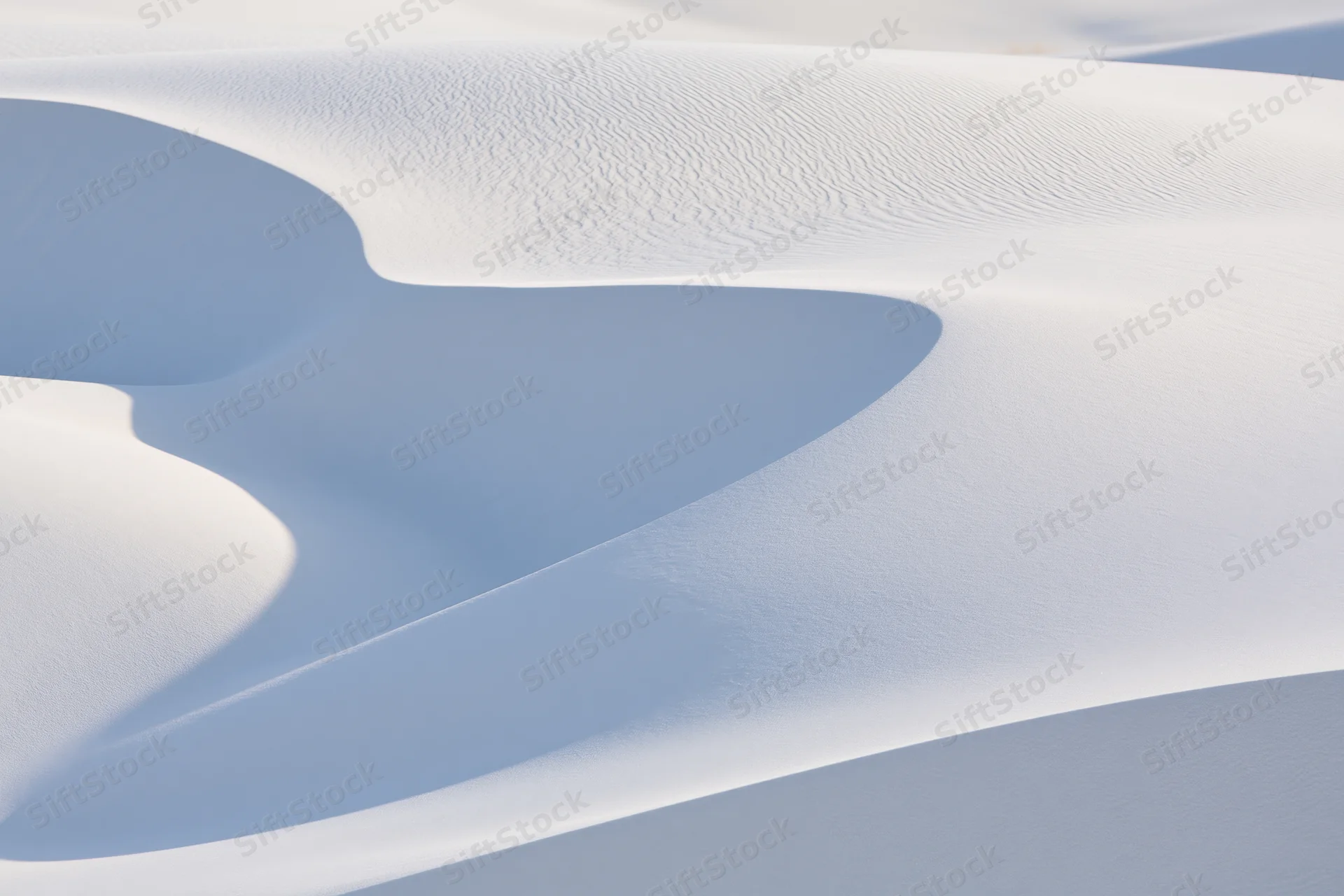White gypsum sand dunes forming smooth curves and shadows in a desert landscape