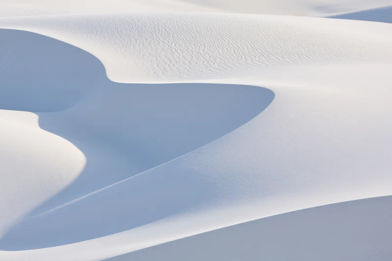 White gypsum sand dunes forming smooth curves and shadows in a desert landscape