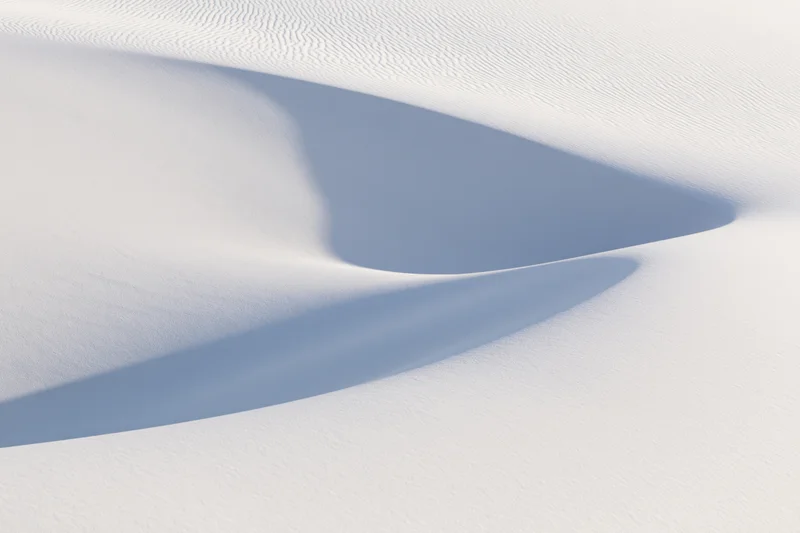 Smooth white gypsum sand dunes with soft shadows and rippled texture in a desert landscape