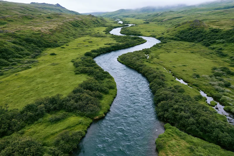 Aerial drone view of a winding river flowing through lush green valley