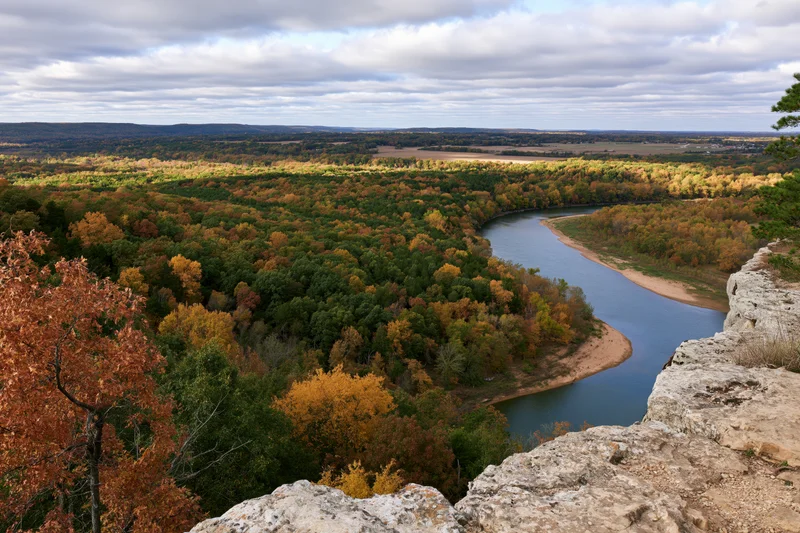 Winding river cutting through autumn forest viewed from rocky overlook