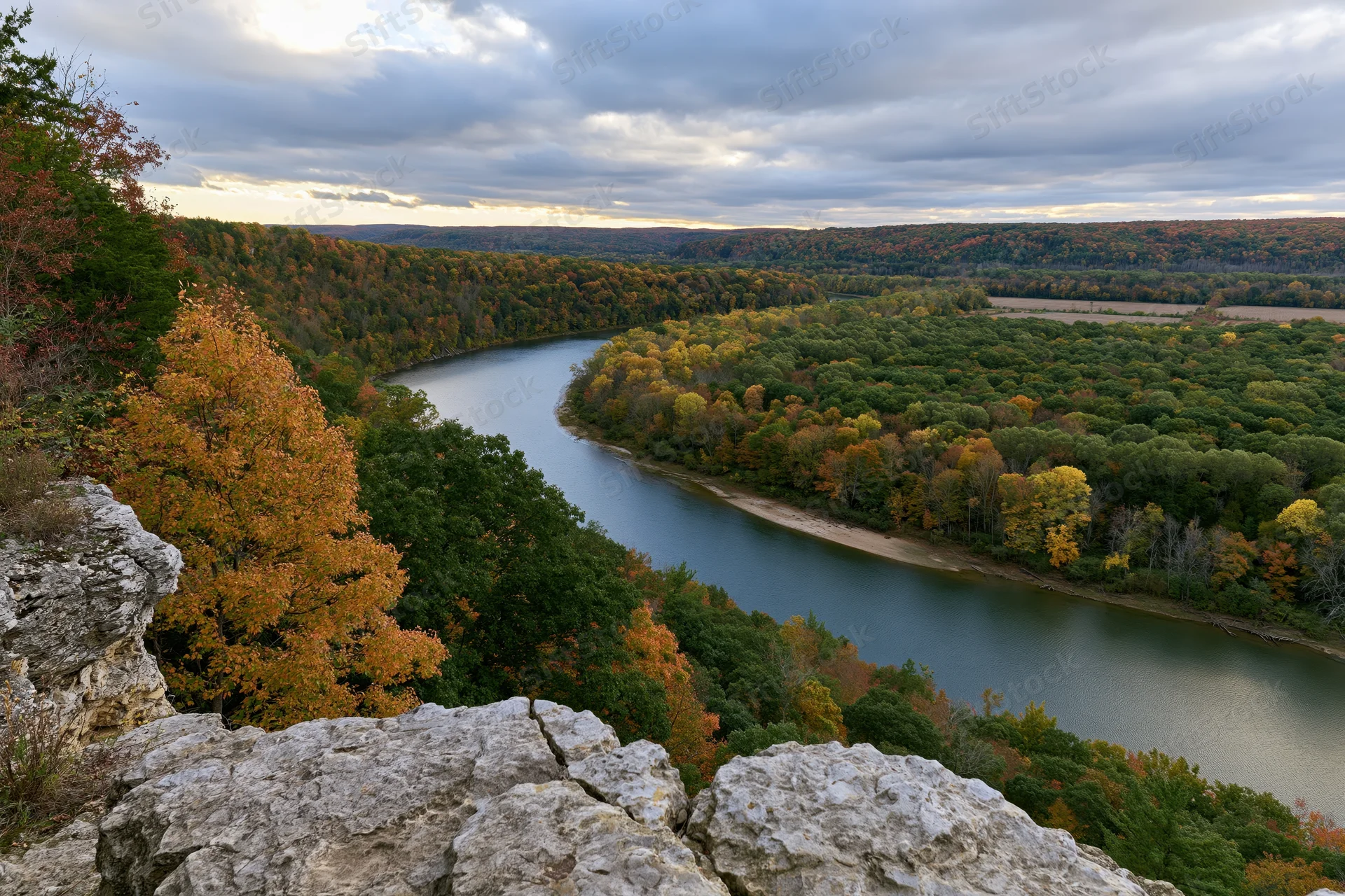 Winding river cutting through forested valley viewed from rocky overlook