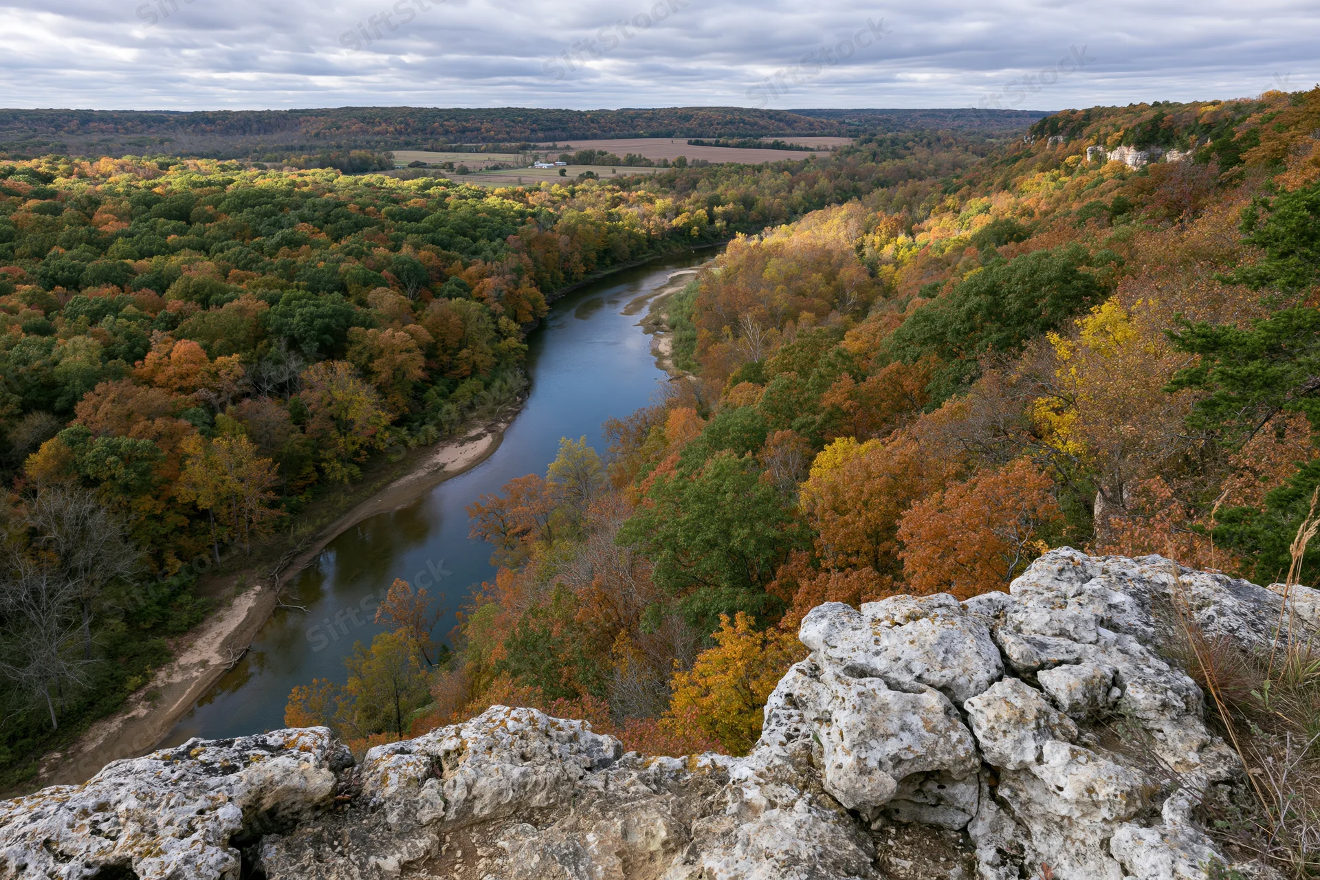 Winding river cutting through autumn forest viewed from rocky cliff overlook