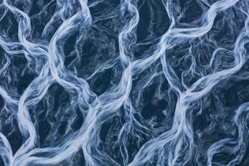 Aerial topdown view of a braided glacial river delta flowing through rocky terrain
