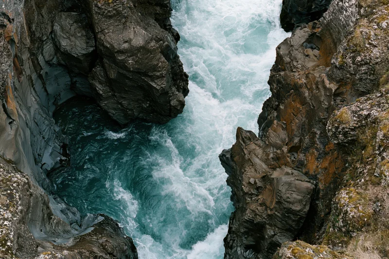 Fast-moving turquoise river flowing through narrow rocky canyon viewed from above