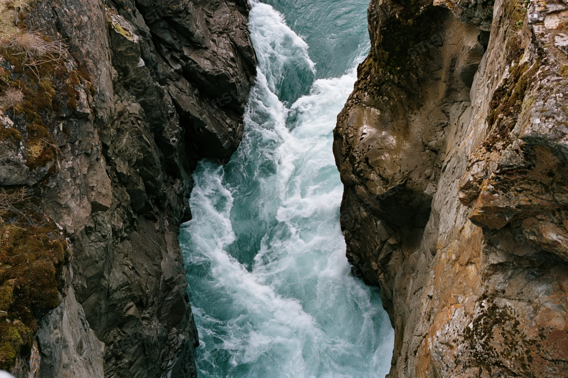 Turquoise river rushing through narrow rocky canyon