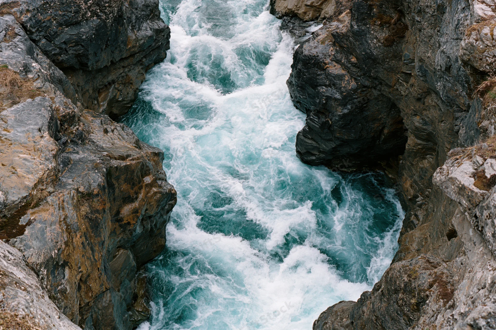 Turbulent river flowing through narrow rocky canyon from above