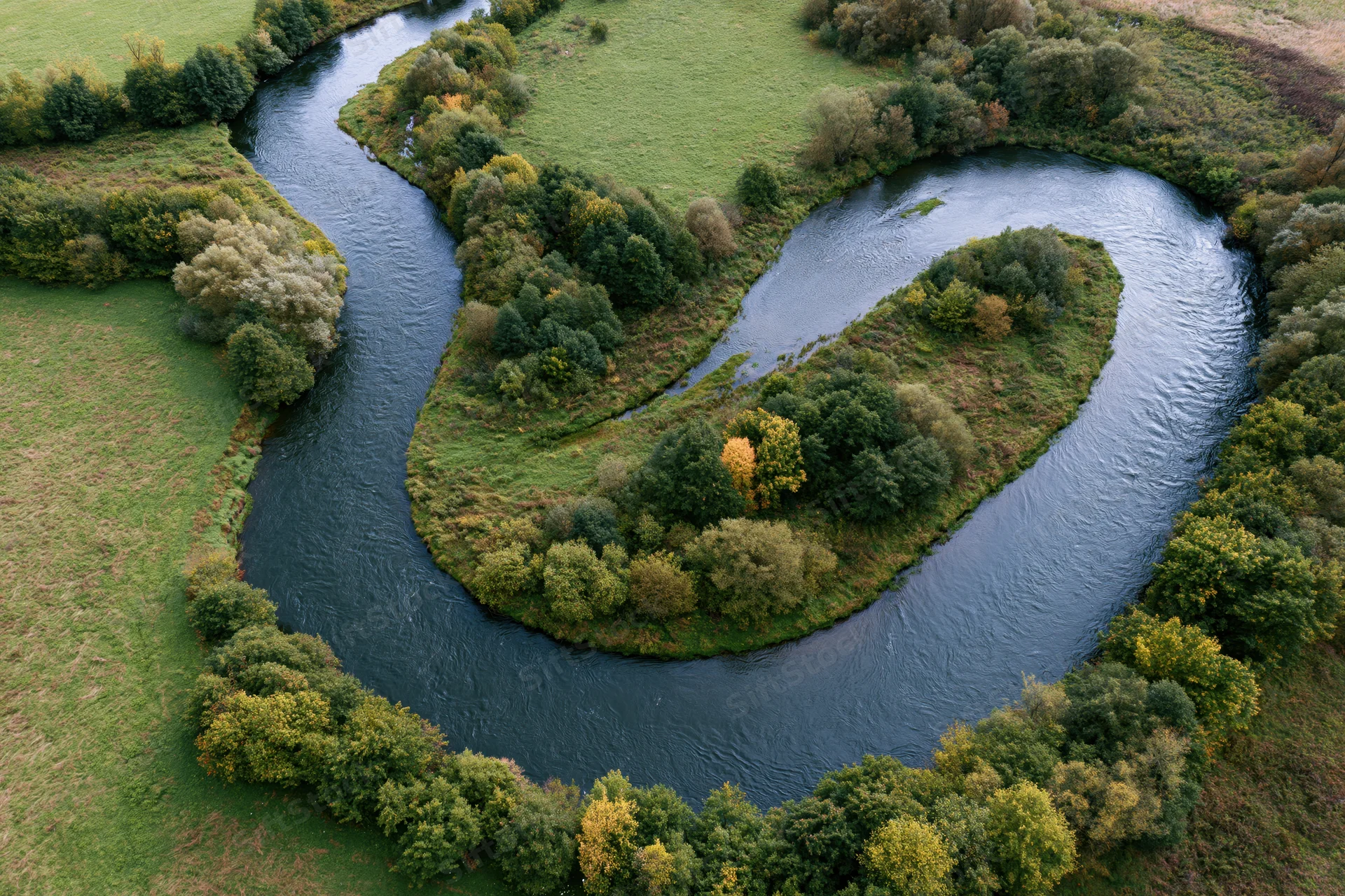 Aerial top-down view of a meandering river forming tight s-shaped bends through green forested countryside