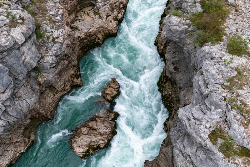 Aerial top-down view of turquoise river flowing through narrow rocky gorge
