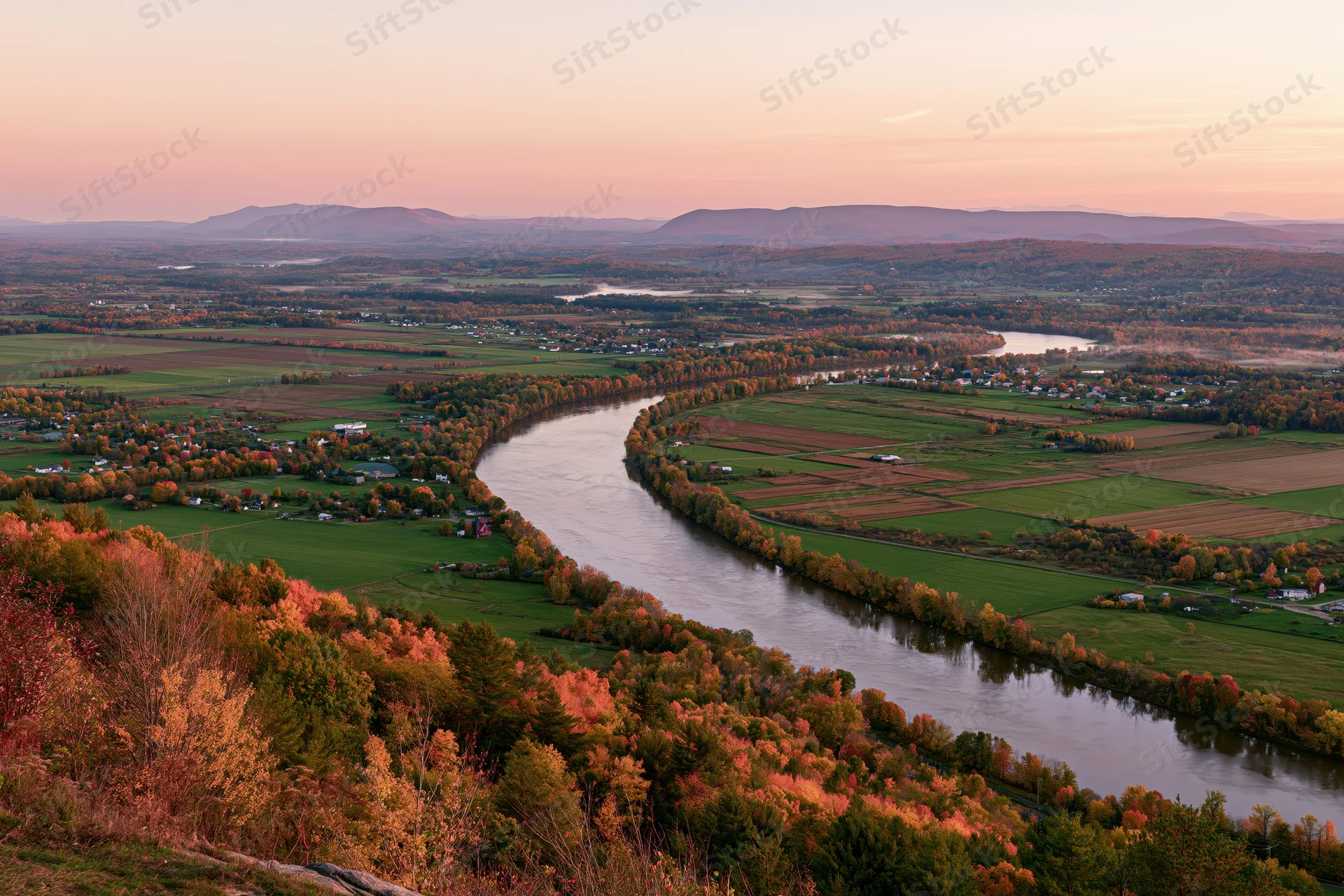Aerial view of a wide river curving through a broad valley with autumn foliage and farmland in new england