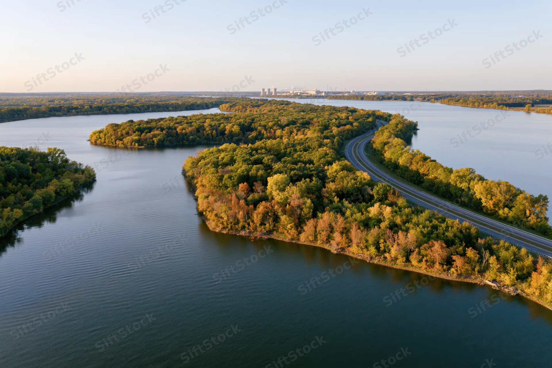 Aerial view of a winding river flowing through forested islands with a curving road alongside