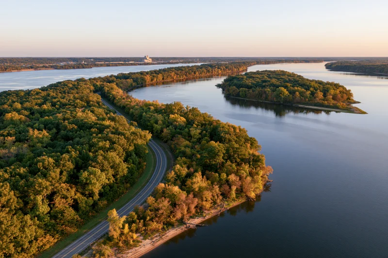 Aerial view of a winding river flowing through forested islands with a curving road along the shore