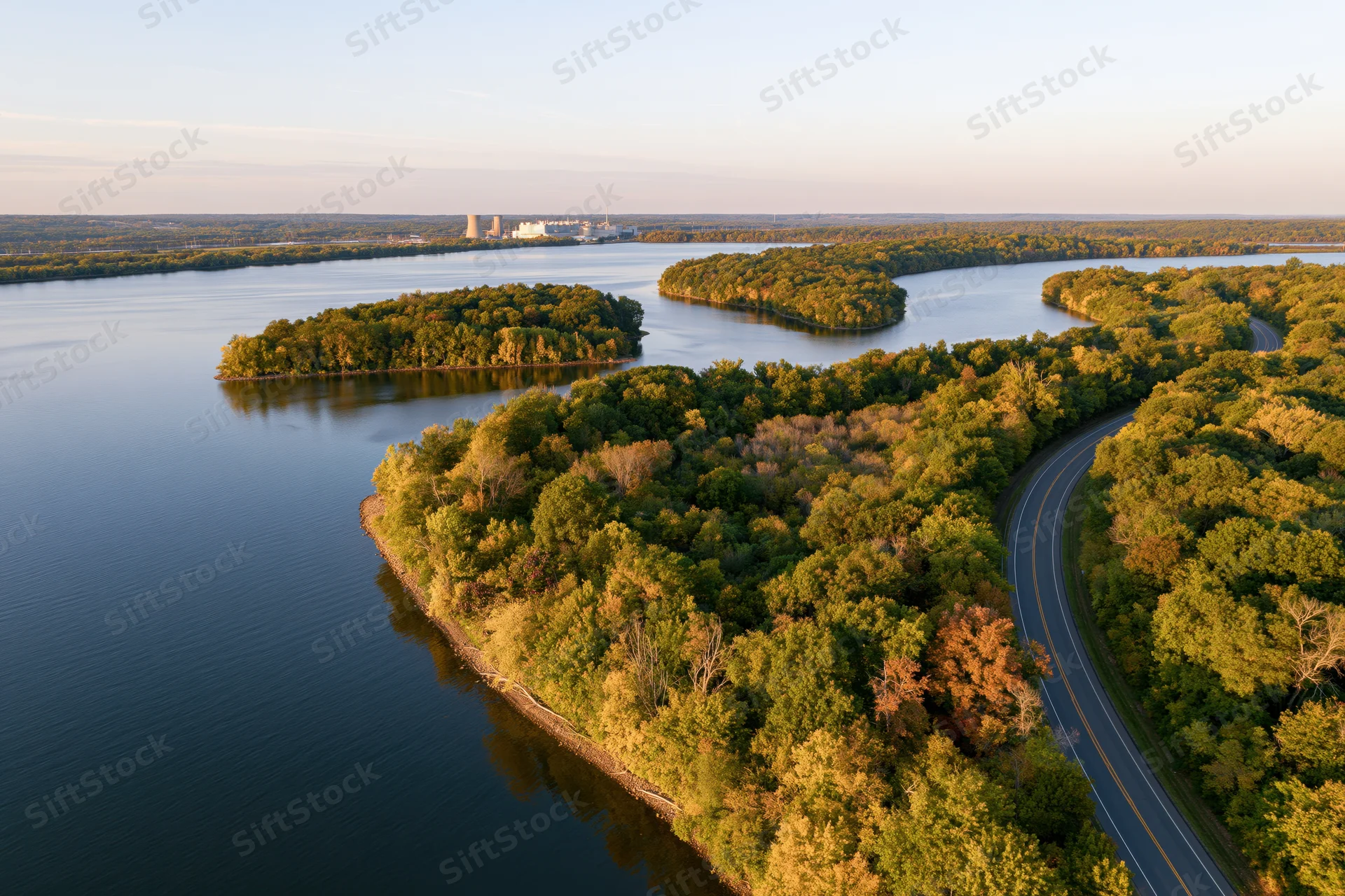 Aerial view of a winding river flowing through forested islands with a curving road along the shoreline