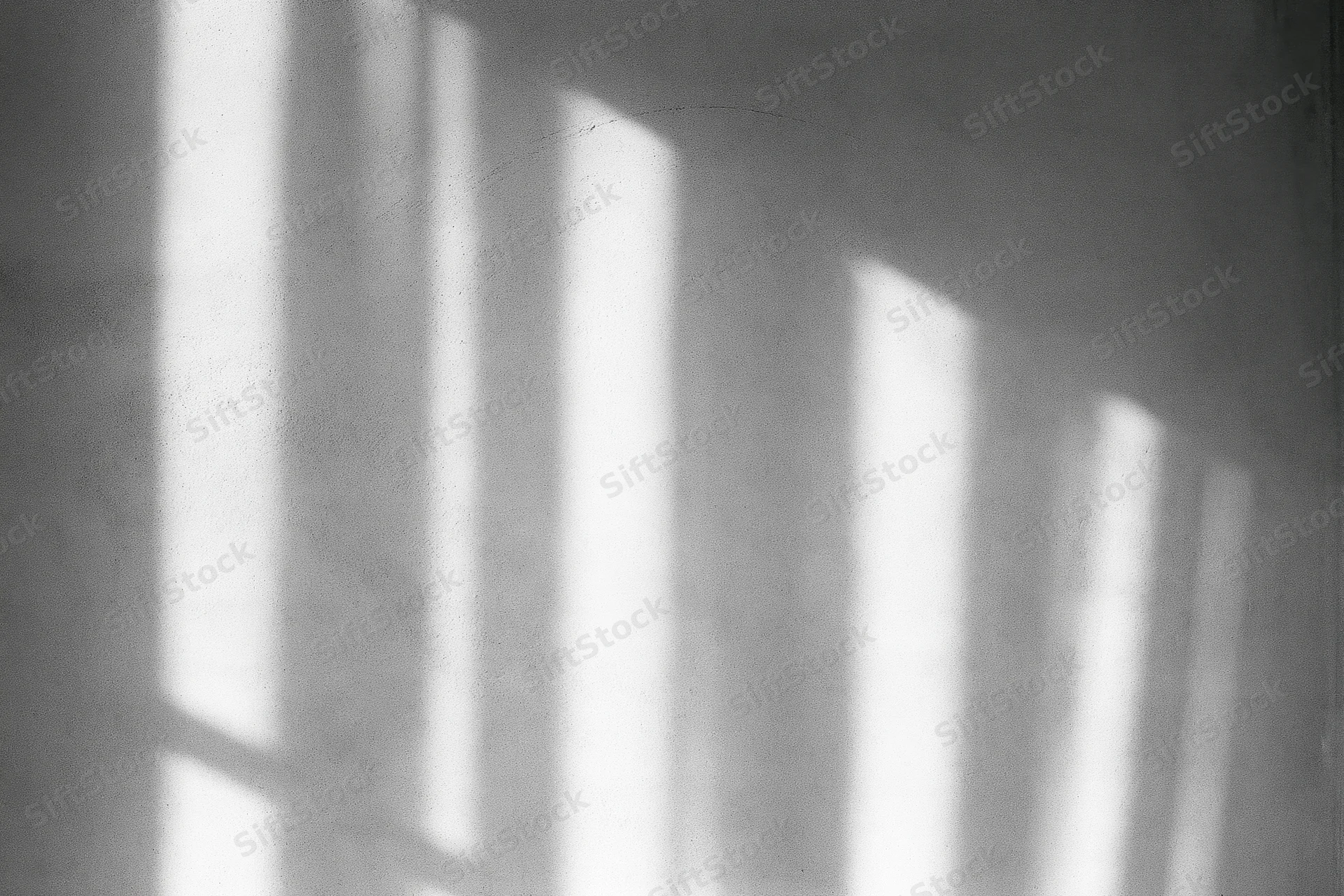 Diagonal light shadows cast on a bare concrete wall indoors