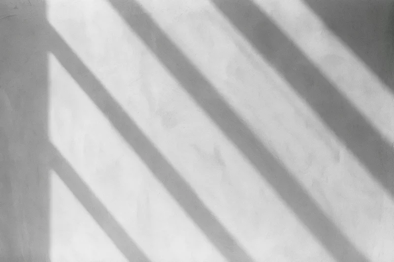 Diagonal shadows from window light on a bare concrete wall