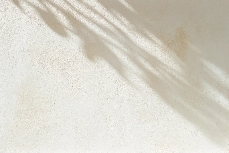 Textured plaster wall with diagonal shadows from natural light