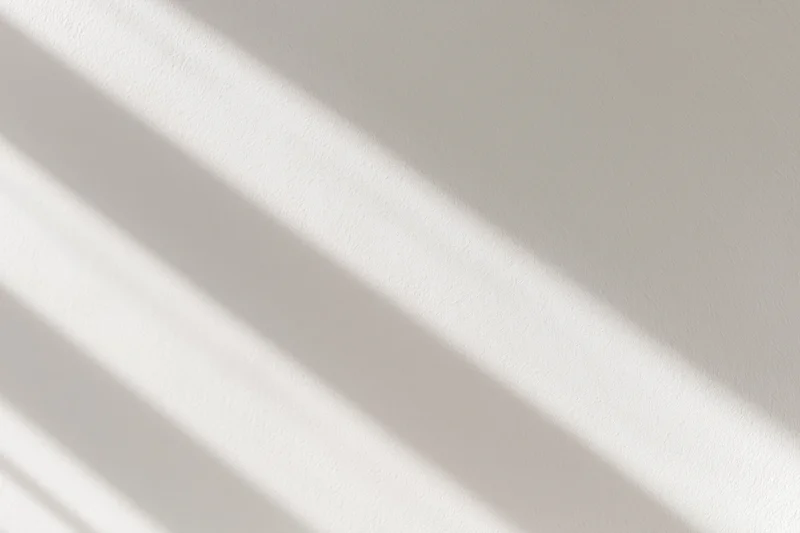 Diagonal light and shadow stripes on a white plaster wall interior