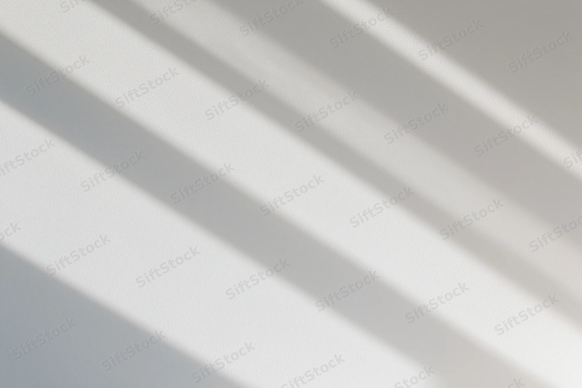 Diagonal light and shadow stripes on a white plaster wall