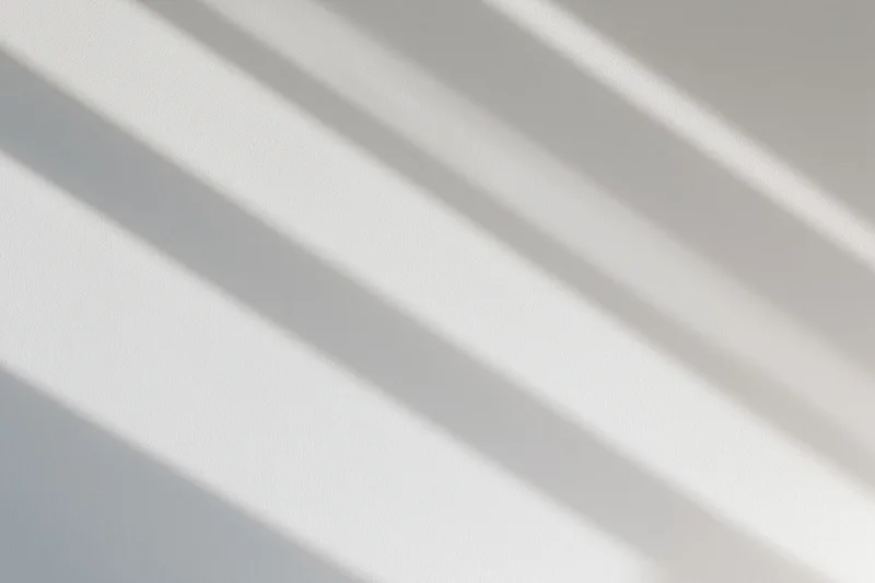Diagonal light and shadow stripes on a white plaster wall