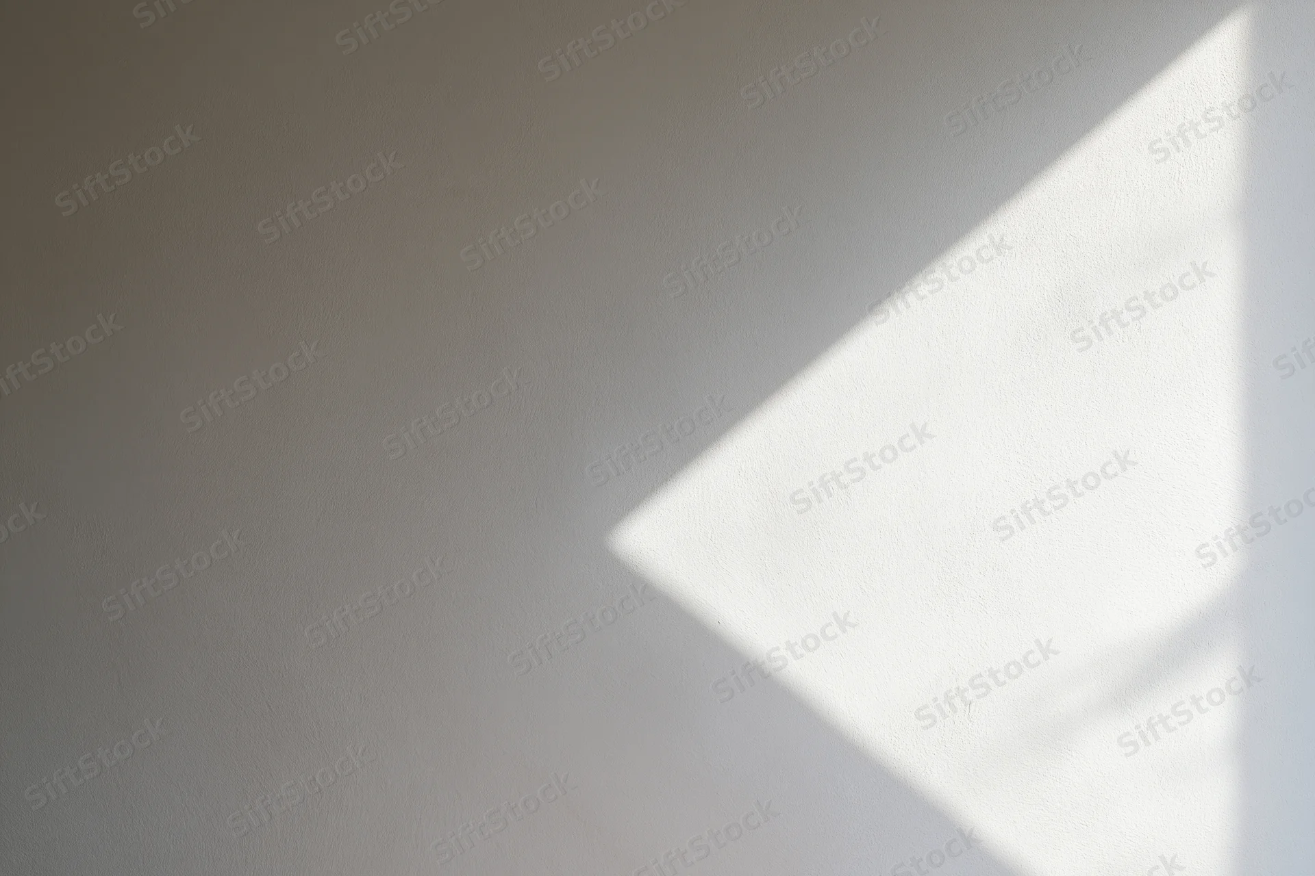 Diagonal beam of sunlight on a white plaster wall in an empty room