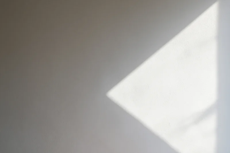 Diagonal beam of sunlight on a white plaster wall in an empty room