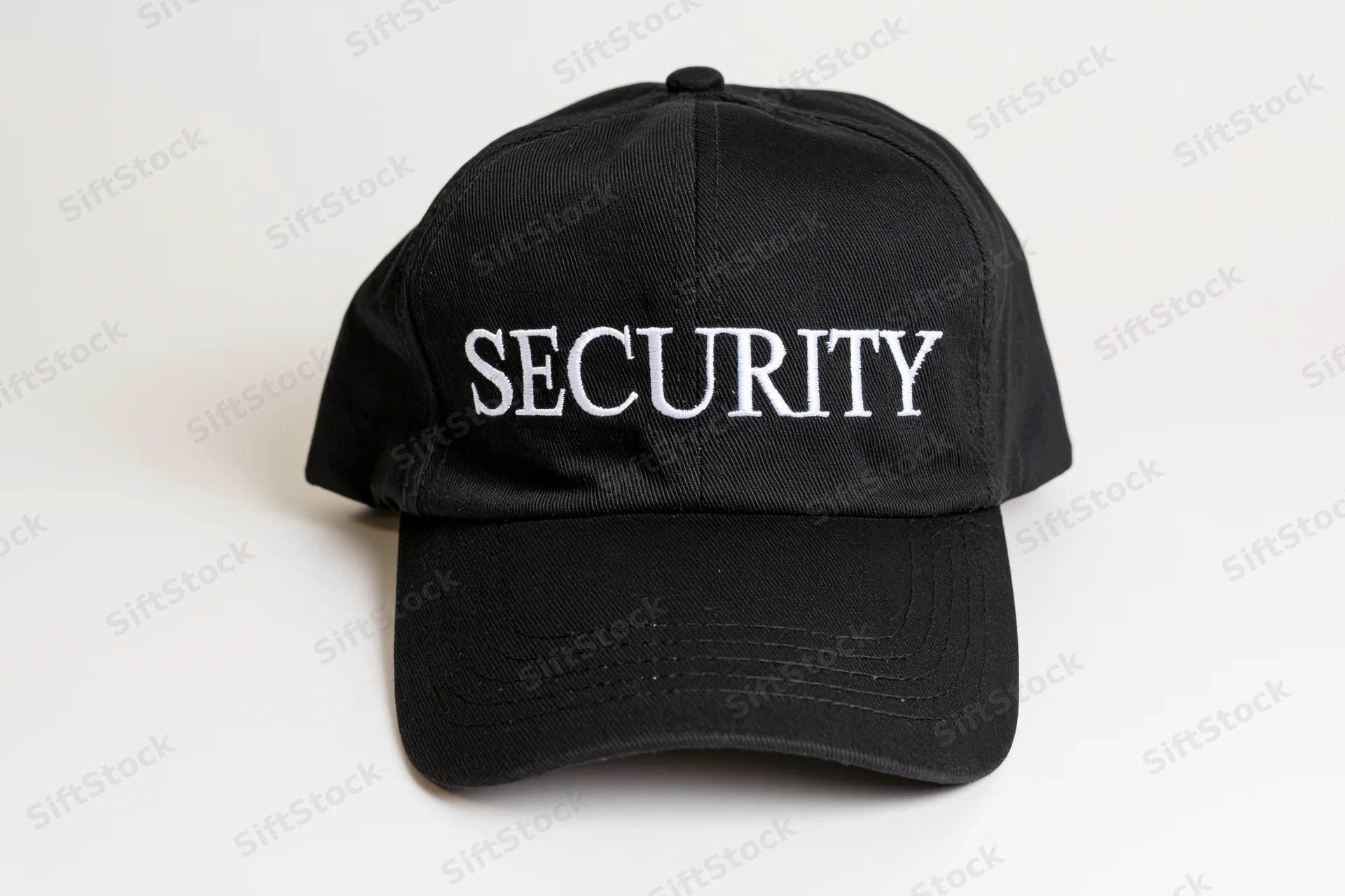Black baseball cap with white embroidered security lettering on white background