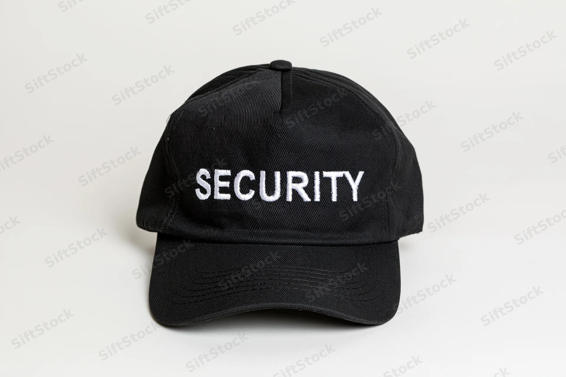 Black baseball cap with white embroidered security lettering on plain white background